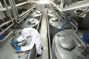 teknisi seragam pelindung putih dan kacamata menutup tangki proses industri di pabrik