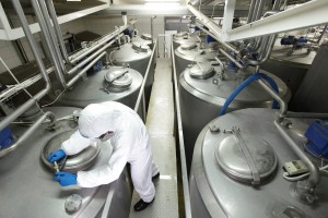 technician in white protective uniform and goggles closing industrial process tank in plant